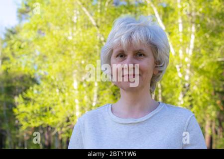 Ritratto di una donna di mezza età che cammina nel parco. Giornata di sole. Buon umore. Spazio per il testo. Foto Stock