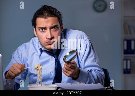 Dipendente affamato che lavora tardi in ufficio Foto Stock