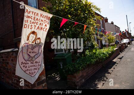 Duncombe Street a Wollaston, dove l'artista Luke Perry ha appeso bunting con messaggi di sostegno per i vicini e i lavoratori chiave, per creare un corridoio di 500 metri di colore attraverso il villaggio delle West Midlands. Perry ha chiesto ai residenti e ai negozianti locali di presentare disegni e messaggi, che poi dipinse a mano e cucì su conchettando con l'aiuto di volontari. Foto Stock