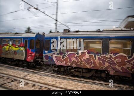 teni, italia maggio 28 2020 : treni che si impanano alla stazione a velocità con persone all'interno e colorate da graffiti Foto Stock