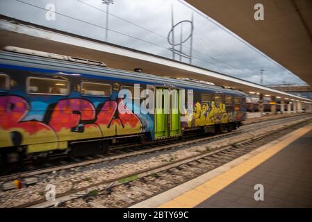 teni, italia maggio 28 2020 : treni che si impanano alla stazione a velocità con persone all'interno e colorate da graffiti Foto Stock