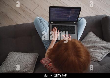 Giovane donna programmatore che lavora su laptop da casa, freelance, social distancing e lavoro remoto Foto Stock