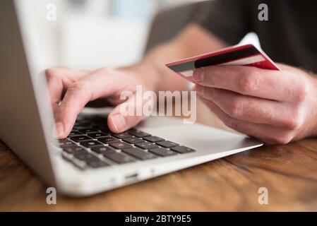 concetto di shopping online, persona che immette le informazioni di pagamento sul computer portatile che tiene in mano debito o carta di credito Foto Stock