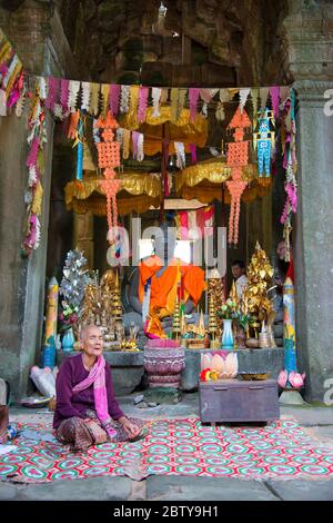 Una donna si siede in preghiera al complesso archeologico di Angkor, Siem Reap, Cambogia, Indocina, Sud-Est asiatico, Asia Foto Stock