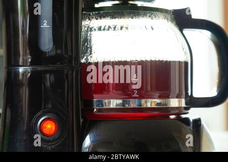 Primo piano di una macchina per il caffè in plastica per preparare una tazza di caffè fresca. Foto Stock