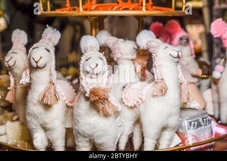 Simpatico gioco imbottito di alpaca con cappelli sorridenti in vendita in un negozio di mercatini di Natale Foto Stock