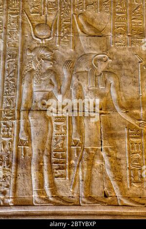 Dea Hathor a sinistra con Dio Horus a destra, bassorilievi Bas, Santuario di Horus, Tempio di Horus, Edfu, Egitto, Africa del Nord, Africa Foto Stock