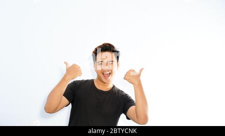 Felice eccitato uomo asiatico casual tenendo i suoi due pollici in su Foto Stock