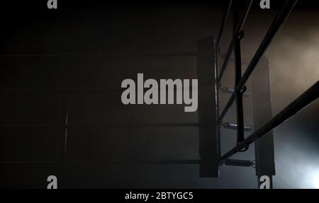 Un closeup drammatico di un angolo poco illuminato di un anello di boxe circondato da corde su uno sfondo scuro isolato - rendering 3D Foto Stock