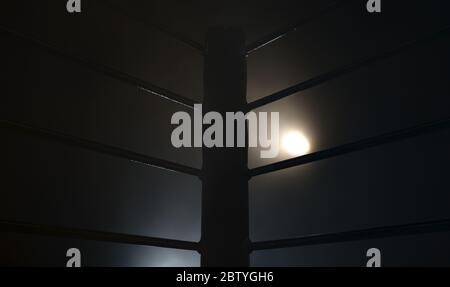 Un closeup drammatico di un angolo poco illuminato di un anello di boxe circondato da corde su uno sfondo scuro isolato - rendering 3D Foto Stock