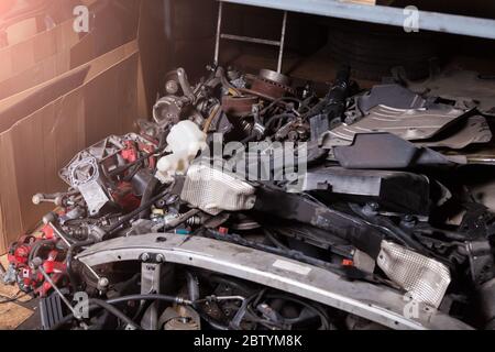 Una pila di parti di ricambio in un magazzino di servizio auto con diverse unità di ferro-plastica auto sul rack inferiore in un'auto-analisi o garage. Foto Stock