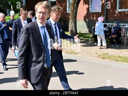 28 maggio 2020, Schleswig-Holstein, Neumünster: Daniel Günther (CDU,l), Ministro Presidente dello Schleswig-Holstein, cammina insieme a Dirk Gärtner, Direttore dell'Ufficio per gli Affari stranieri, dietro una recinzione protettiva sul terreno dell'alloggio. Durante la visita ha annunciato il nuovo nome dell'autorità. In futuro sarà chiamato 'Ufficio di stato per l'immigrazione e i rifugiati. Foto: Carsten Rehder/dpa Foto Stock