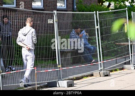 28 maggio 2020, Schleswig-Holstein, Neumünster: Dietro una recinzione come misura di protezione contro le infezioni, i rifugiati sono visti nei locali dell'Ufficio di Stato per gli Affari stranieri. Durante una visita, il primo ministro Guenther ha annunciato il nuovo nome dell'autorità. In futuro, sarà chiamato 'Ufficio di stato per l'immigrazione e i rifugiati. Foto: Carsten Rehder/dpa Foto Stock