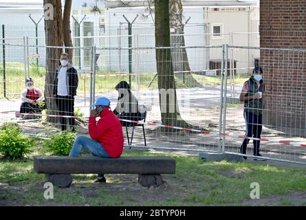 28 maggio 2020, Schleswig-Holstein, Neumünster: Dietro una recinzione come misura di protezione contro le infezioni, i rifugiati sono visti nei locali dell'Ufficio di Stato per gli Affari stranieri. Durante una visita, il primo ministro Guenther ha annunciato il nuovo nome dell'autorità. In futuro, sarà chiamato 'Ufficio di stato per l'immigrazione e i rifugiati. Foto: Carsten Rehder/dpa Foto Stock