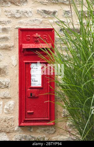 Tradizionale scatola rossa posta su muro di pietra, Burford, Cotswolds, Inghilterra, Regno Unito Foto Stock