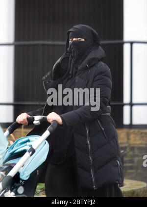 Una donna cammina su una strada britannica indossando una copertura Burka faccia, Birmingham, Inghilterra. Foto Stock