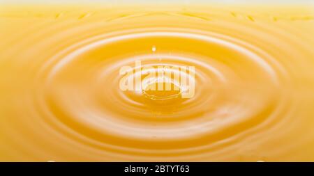 le onde dopo alcune gocce di succo d'arancia. Foto Stock