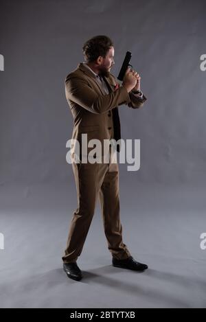 Immagine isolata di un poliziotto coperto con una pistola contro uno sfondo semplice, ideale per il design di copertina e giacche libro ebook Foto Stock