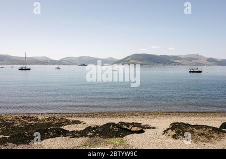 Vista sul Firth di Clyde verso Dunoon dalla spiaggia di Gourock con barche ancorate in acqua. Foto Stock