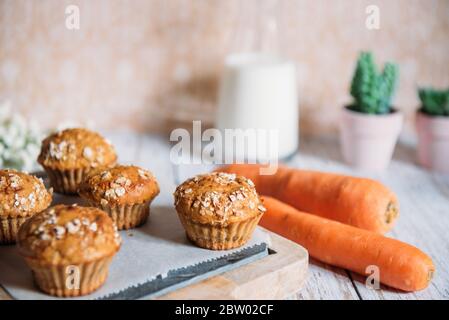 Muffin a grani interi con mele, carote e noci su un tagliere rustico su sfondo chiaro, cibo vegetariano sano, senza latticini. Foto Stock