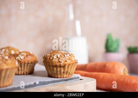 Muffin a grani interi con mele, carote e noci su un tagliere rustico su sfondo chiaro, cibo vegetariano sano, senza latticini. Foto Stock