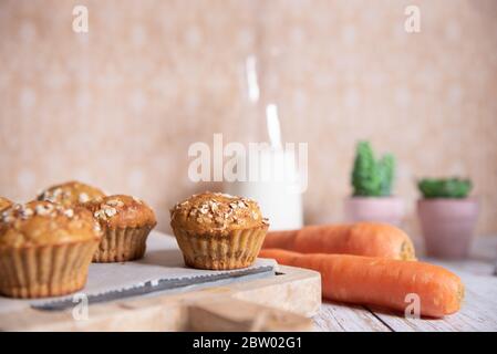 Muffin a grani interi con mele, carote e noci su un tagliere rustico su sfondo chiaro, cibo vegetariano sano, senza latticini. Foto Stock