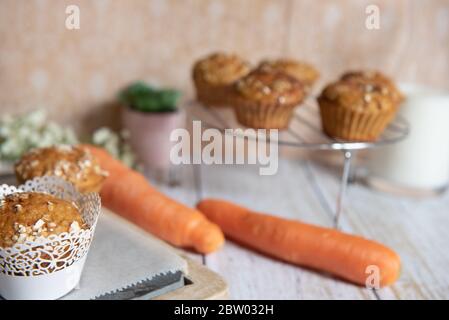 Muffin a grani interi con mele, carote e noci su un tagliere rustico su sfondo chiaro, cibo vegetariano sano, senza latticini Foto Stock