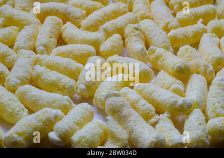 Croccanti ariosi, polsini di mais, spuntini di puffcorn sfondo. Shot dettagliato di puffcorn pronto per il consumo. Dolci croccanti. Foto Stock