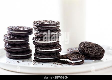 Biscotti Oreo impilati con latte su sfondo bianco Foto Stock