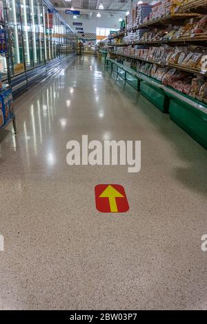 Toronto, Canada, maggio 2020 - misure di protezione epidemica nei negozi di alimentari - segno di freccia giallo sul pavimento per lo shopping direzionale sicuro Foto Stock