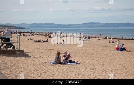 Portobello, Edimburgo, Scozia. 28 maggio 2020. 25 gradi tardo pomeriggio al mare. La spiaggia e la passeggiata ragionevolmente trafficate con la polizia in presenza continuano con il passaggio ma non si preoccupano di parlare con chiunque riguardo sedersi intorno mentre il primo ministro scozzese allevia alcune delle restrizioni per il pubblico scozzese. Foto Stock