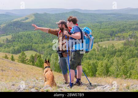 Padre, figlio e il loro cane viaggiano in natura, escursioni in montagna. Concetto di viaggio per famiglie. Foto Stock