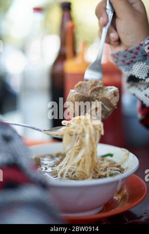 Zuppa di tagliatelle con polpette e verdure su un piatto. Gustosi piatti asiatici Foto Stock