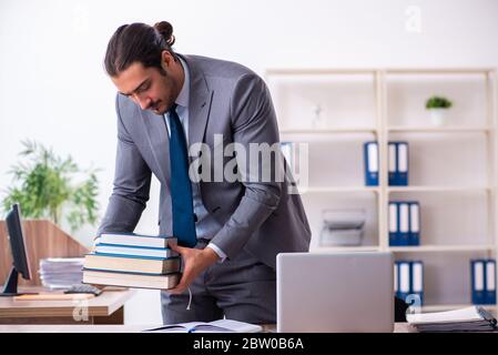 Giovane uomo d'affari che legge libri sul posto di lavoro Foto Stock