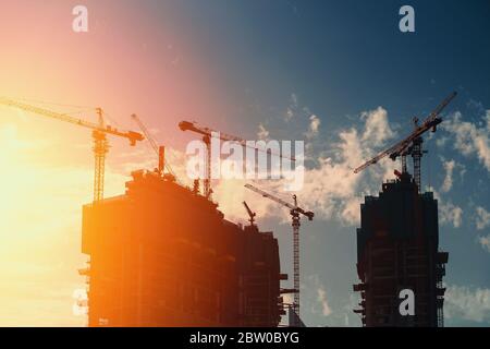 Edifici di costruzione moderna grattacieli con gru industriali opere a Dubai. Rapido sviluppo urbano e urbano. Foto Stock