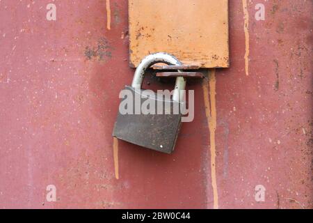 Un moderno lucchetto in ferro pende sulla porta in acciaio. Porta chiusa a chiave per la sede. Concetto di protezione, incarcerazione, protezione, prigione. Foto Stock