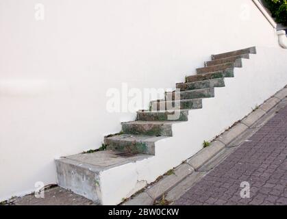Undici gradini concreti che salgono su un muro, salendo da nessuna parte Foto Stock