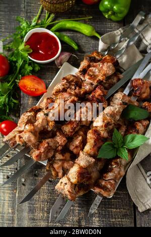 Menu barbecue estivo. Spiedini di carne alla griglia su un rustico tavolo di legno. Foto Stock