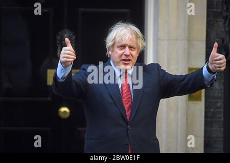 Il primo Ministro Boris Johnson entra a far parte del settimanale Clap for Carers al di fuori della sua residenza ufficiale di Londra a Downing Street. Foto Stock