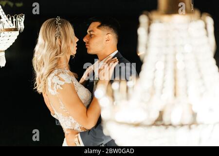 Felice newlywed in piedi nelle luci del lampadario. Il momento prima di baciare. La fine del giorno di nozze Foto Stock