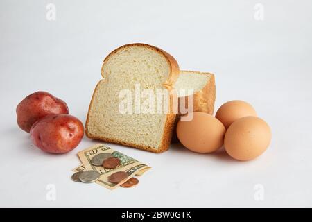 Studio di alimenti di base pane, uova e patate con valuta che illustra il costo del cibo e l'economia. Foto Stock