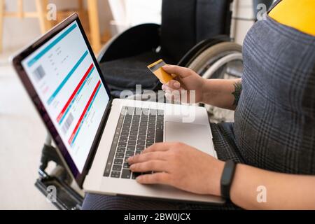 Primo piano di una donna inriconoscibile che controlla le informazioni sui voli e paga i biglietti con carta di credito Foto Stock