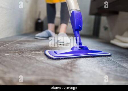 Primo piano di donna che usa la mop bagnata mentre pulisce il pavimento nella casa. Foto Stock