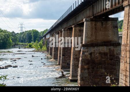 Un ponte ferroviario fatto di pietra e metallo che attraversa il fiume Broad in Columbia, Carolina del Sud, preso dal canale Columbia e dal Riverfront Park Foto Stock