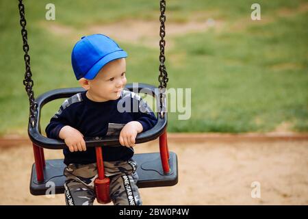 ragazzo di 1-2 anni seduto su un altalena, parco giochi, primo piano Foto Stock