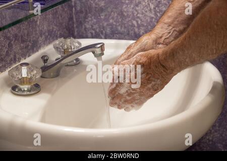 Mani che si insaporono con il lavello del bagno dell'acqua corrente Foto Stock