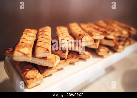 Sfogliatina di dessert tradizionale italiano appena sfornata su vassoio bianco. Biscotti sfoglia smaltati. Concetto di celebrazione, festa, compleanno o matrimonio. Foto Stock