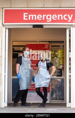 Personale sanitario all'ingresso del Dipartimento di emergenza presso il Southend University Hospital, Essex, Regno Unito. Due infermieri in DPI di base con maschere chirurgiche per il viso. COVID-19 Foto Stock