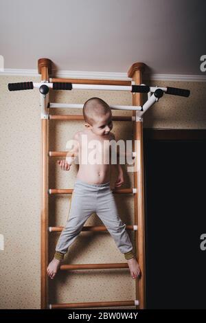 Allenamento domestico. Il ragazzo salì la parete di arrampicata. Foto Stock