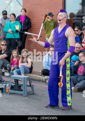 Saint John, New Brunswick, Canada - 13 luglio 2017: Festival annuale dei Buskers. Un uomo con capelli viola mohawk e vestito in juggles viola fuoco battoni. Foto Stock